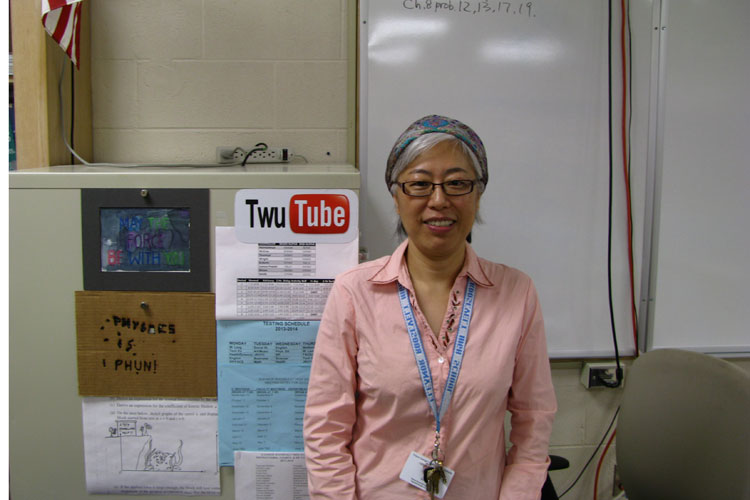 Ms. Twu, in front of her classroom advertisement for her videos. 
