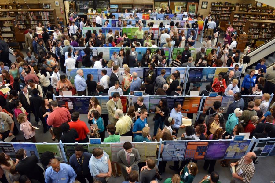 Students, parents, teachers, mentors and guests look at the posters during the 2015 Research Practicum Symposium. 