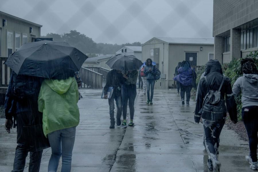 Students walking through todays rain at the back of the school