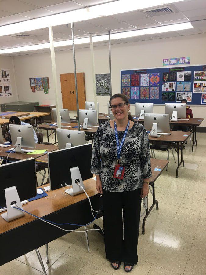 Ms.Connealy posing with computers in her classroom.