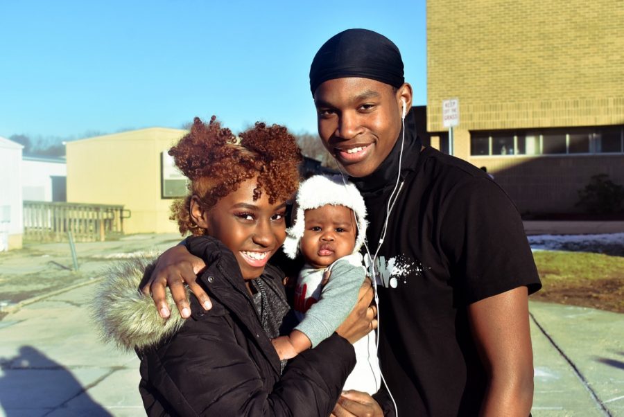 An ERHS couple poses with their baby outside of the school. 